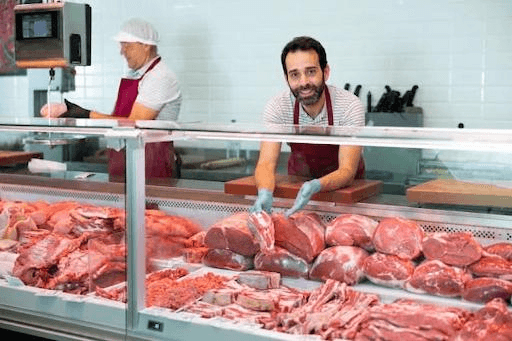 Professionals atenent un taulell de carnisseria amb carn fresca